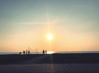 Silhouette people on beach against sky during sunset