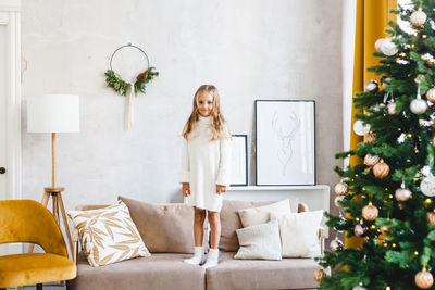 Full length of girl standing on sofa at home