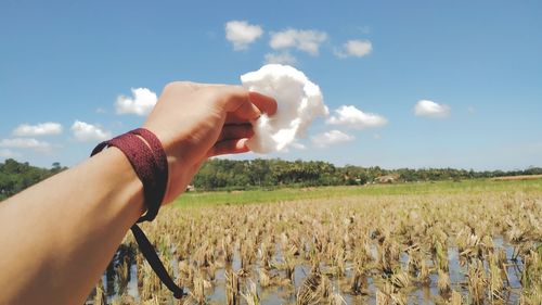 Midsection of person holding hands on field against sky