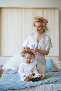 Mom and daughter in white coats with curlers in their hair. happy loving