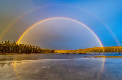 Scenic view of double rainbow with reflection off frozen lake