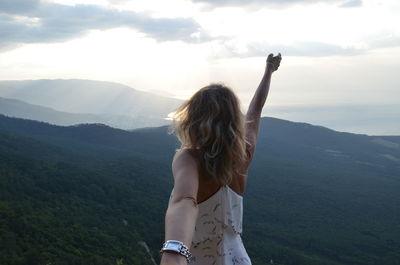 Rear view of wife standing on mountain against sky