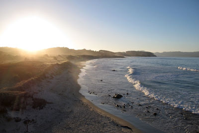 Scenic view of beach against clear sky during sunset