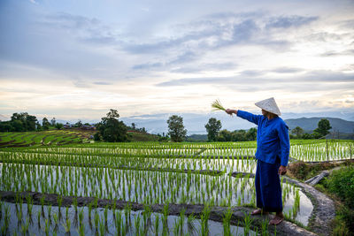 Full length of farmer standing at paddy field