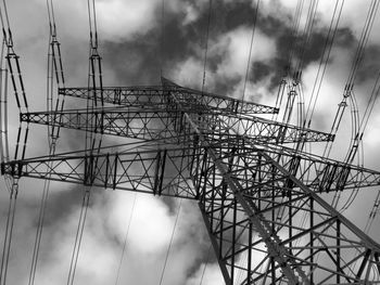 Low angle view of electricity pylon against cloudy sky