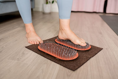Cropped of woman standing on wooden sadhu board with nails or a fire board, a yoga desk 