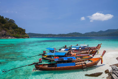 Boat moored on sea shore against sky