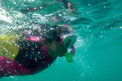 Kid snorkelling in sea with reflection, underwater shot