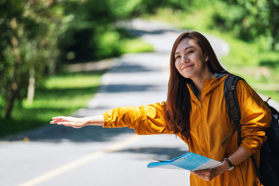 Young woman with arms raised standing outdoors