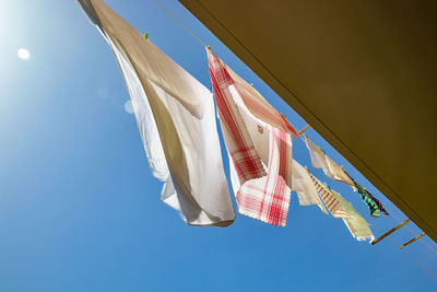 Low angle view of clothes hanging against blue sky