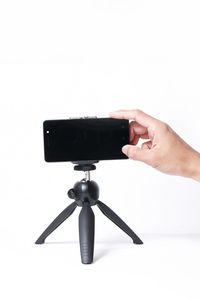 Close-up of hand holding camera over white background