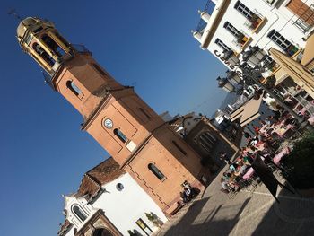 Tilt image of clock tower and buildings in city during sunny day