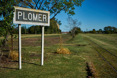 Road sign on field against sky