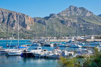 Sailboats moored at harbor against clear blue sky