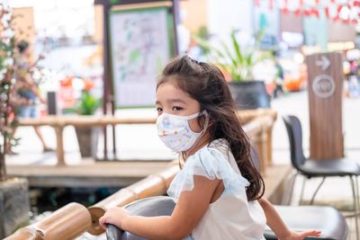 Cute girl wearing mask sitting at cafe