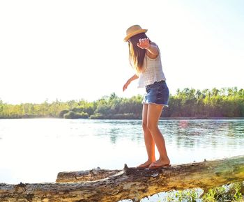 Rear view of woman standing by lake against sky