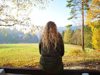 Rear view of woman standing on field against sky