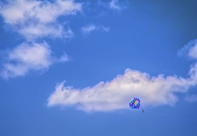 Low angle view of person parasailing against blue sky