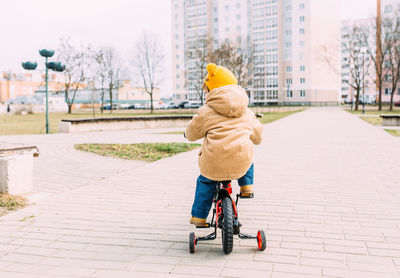A small child learns to ride a bike for the first time in the city in spring