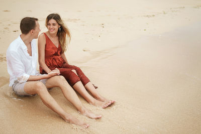 Young woman sitting on sand at beach