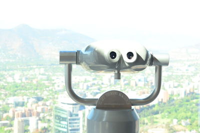 Close-up of coin-operated binoculars against cityscape