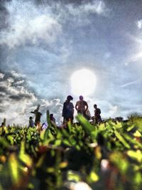 People on grassy field against cloudy sky