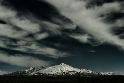 Scenic view of snow covered mountains against cloudy sky