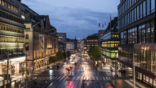 Cars on road amidst buildings in city at dusk