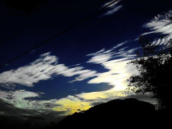 Low angle view of trees against cloudy sky