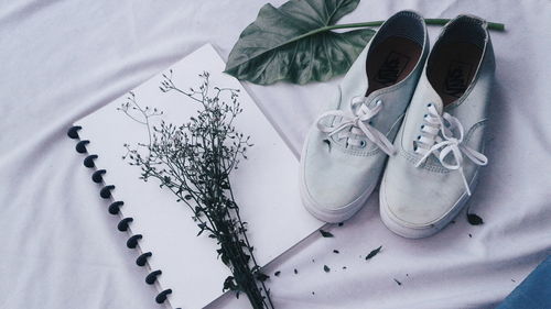 High angle view of book with shoes and plant on fabric