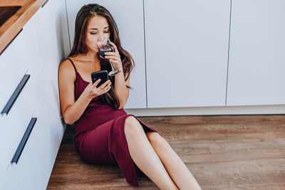 Young woman using mobile phone while sitting on floor