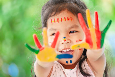 Close-up of smiling girl showing colorful body paint on hands