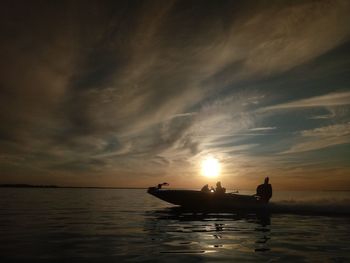 Silhouette boat in sea against sky during sunset