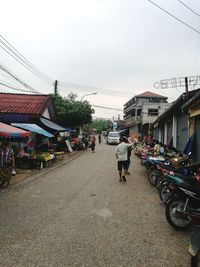 People walking on road in city against sky