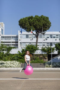 Female professional bouncing with ball on road during sunny day