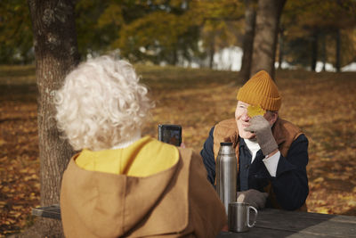 Senior woman photographing her partner in park