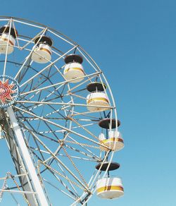 Low angle view of ferris wheel against clear blue sky