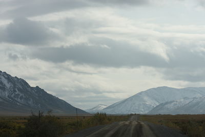 Road leading towards mountains against sky