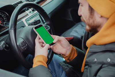 Millennial man drive the car and using mobile app , green screen. high quality photo