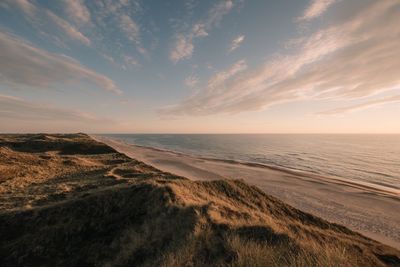 Scenic view of sea against cloudy sky during sunset