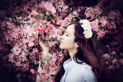 Close-up of young woman with flowers on tree