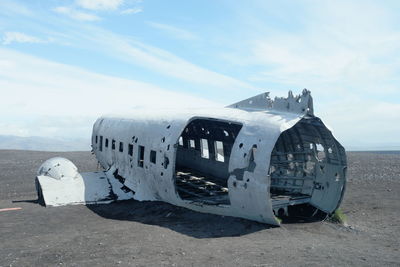 Abandoned airplane on beach against sky