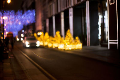 Illuminated street amidst buildings in city at night