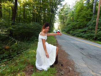 Portrait of woman hitchhiking in forest
