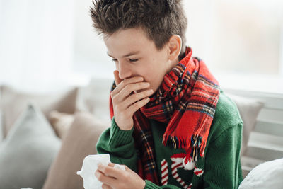 Close-up of boy sneezing at home