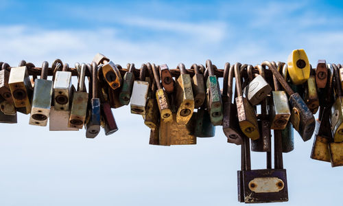 Close-up of padlocks hanging on metal against sky