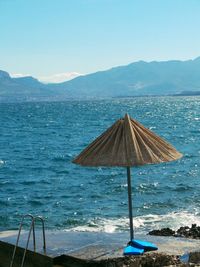 Parasol at jetty against clear blue sky