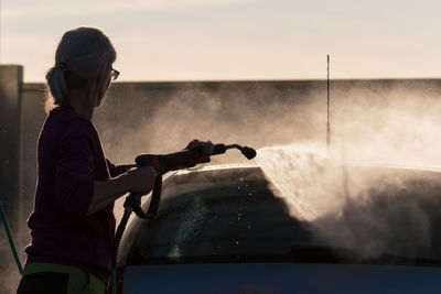 Silhouette woman washing car