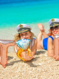 Portrait of smiling bride with bridesmaid lying at beach