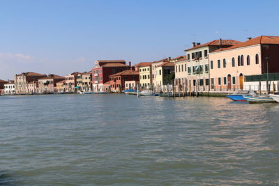 Buildings by sea against clear sky in city